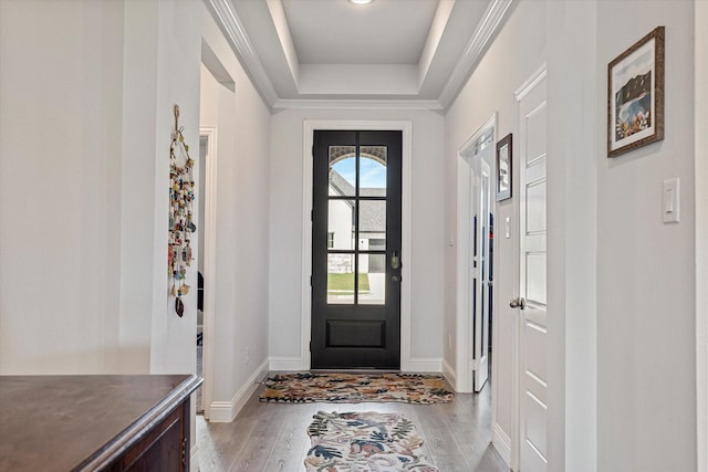 doorway featuring baseboards, light wood-style flooring, and a raised ceiling