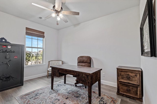 office space featuring baseboards, ceiling fan, wood finished floors, and visible vents