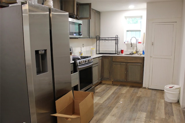 kitchen featuring a sink, light countertops, light wood finished floors, stainless steel appliances, and recessed lighting