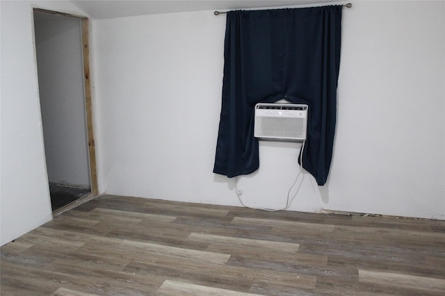 spare room with an AC wall unit and wood finished floors
