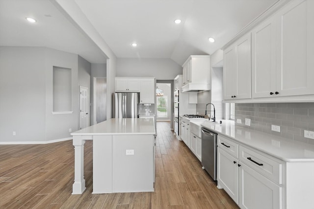kitchen with a breakfast bar area, decorative backsplash, stainless steel appliances, light wood-style floors, and a kitchen island
