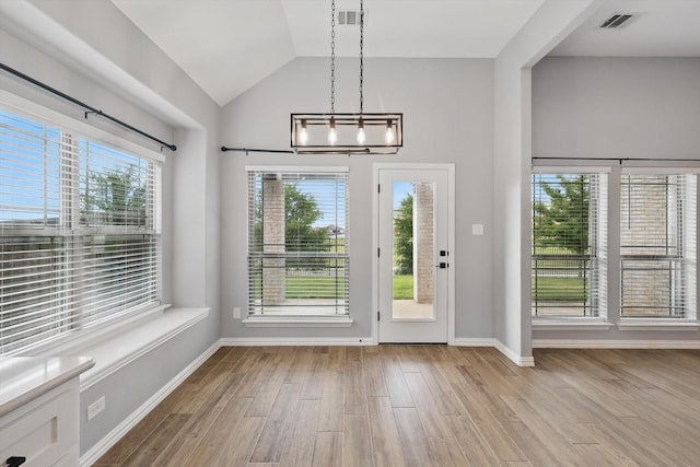 doorway featuring baseboards, an inviting chandelier, visible vents, vaulted ceiling, and wood finished floors
