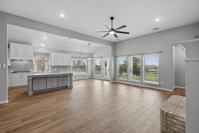 kitchen featuring ceiling fan with notable chandelier, visible vents, vaulted ceiling, open floor plan, and light countertops
