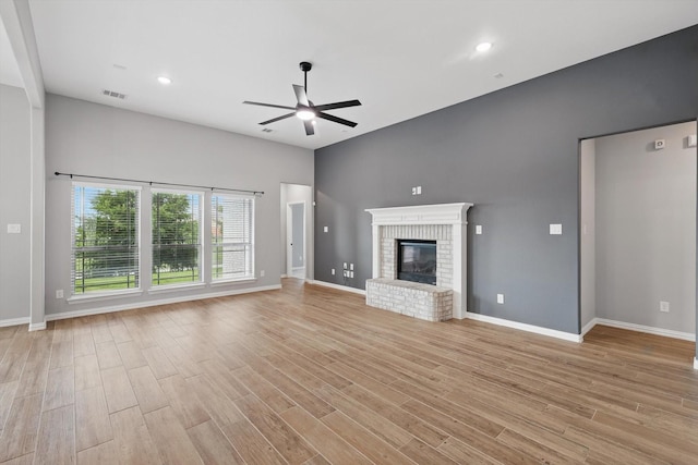 unfurnished living room featuring light wood-type flooring, visible vents, a fireplace, ceiling fan, and baseboards