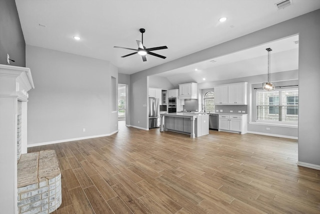 unfurnished living room with baseboards, visible vents, light wood-style flooring, and a ceiling fan