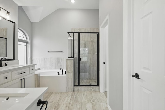 bathroom featuring a stall shower, vanity, a bath, and vaulted ceiling