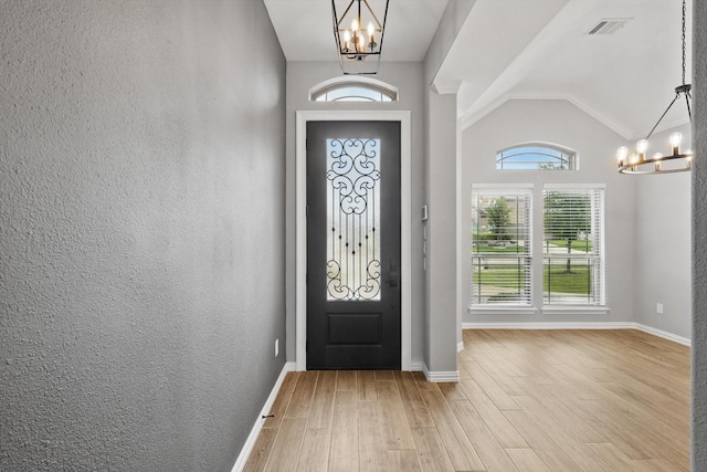 foyer with a chandelier, wood finished floors, visible vents, and lofted ceiling