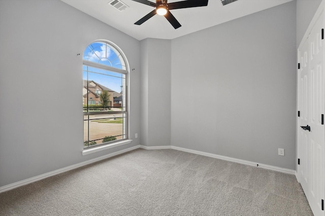 spare room with a ceiling fan, carpet flooring, visible vents, and baseboards