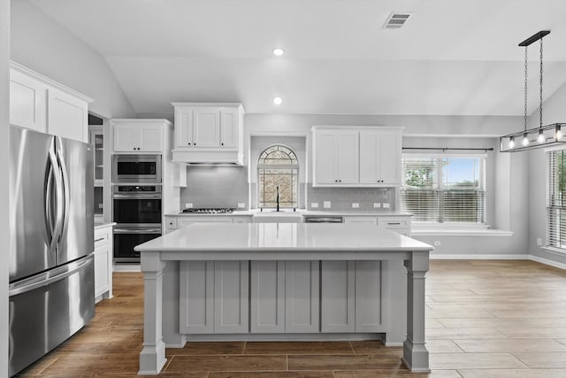 kitchen featuring light countertops, appliances with stainless steel finishes, a sink, and vaulted ceiling