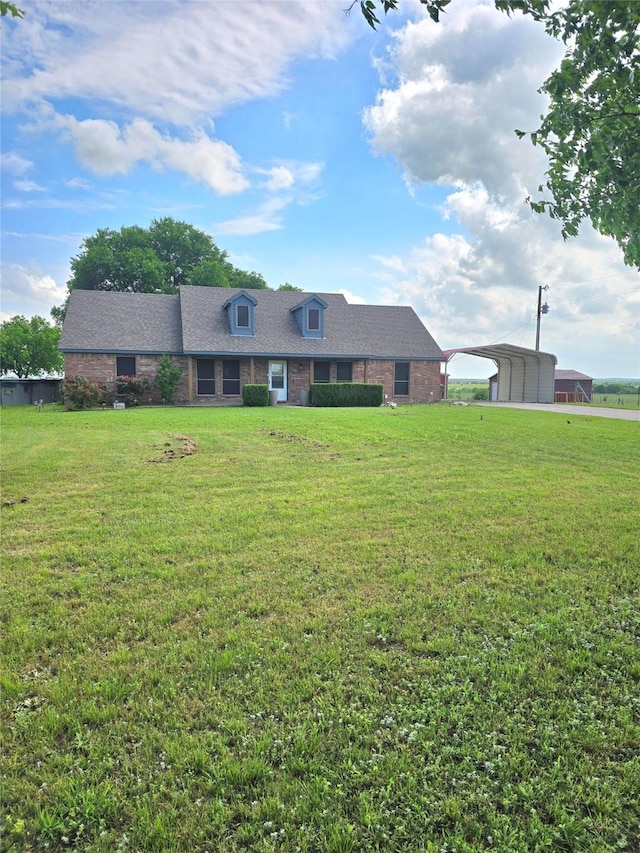view of property with brick siding, a shingled roof, a front yard, and a carport