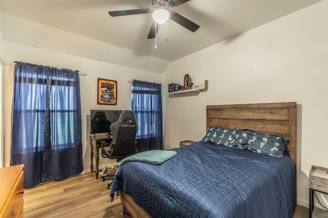 bedroom with ceiling fan, vaulted ceiling, and wood finished floors