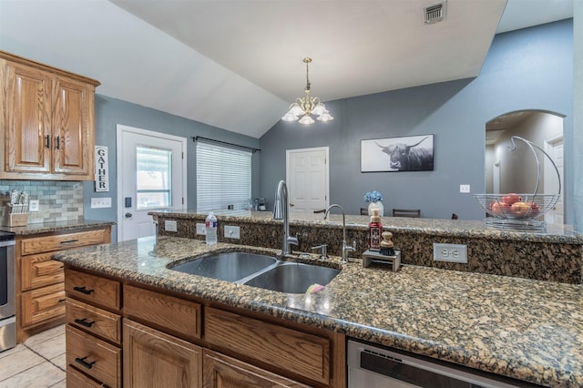kitchen featuring a sink, arched walkways, dark stone counters, stainless steel dishwasher, and visible vents