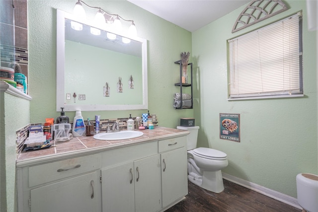 bathroom with vanity, baseboards, toilet, and wood finished floors
