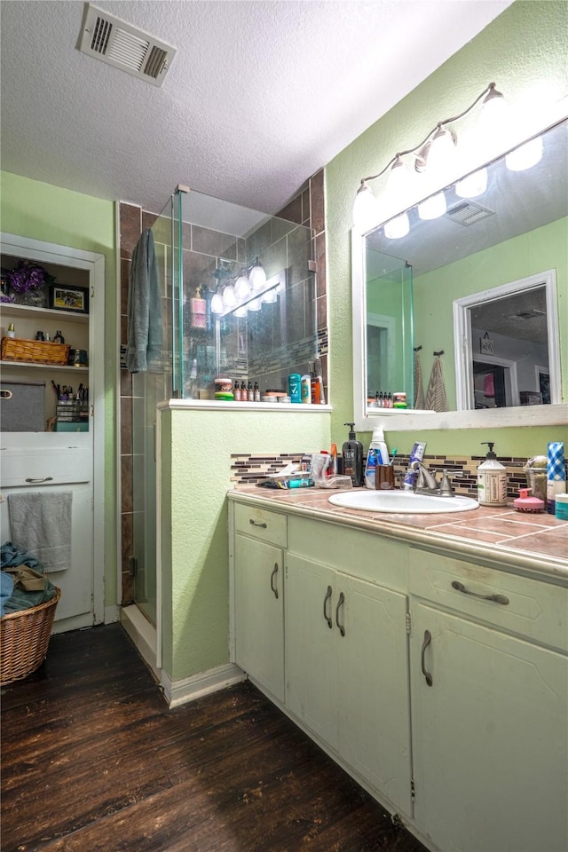 full bathroom featuring visible vents, a textured ceiling, wood finished floors, and a shower stall