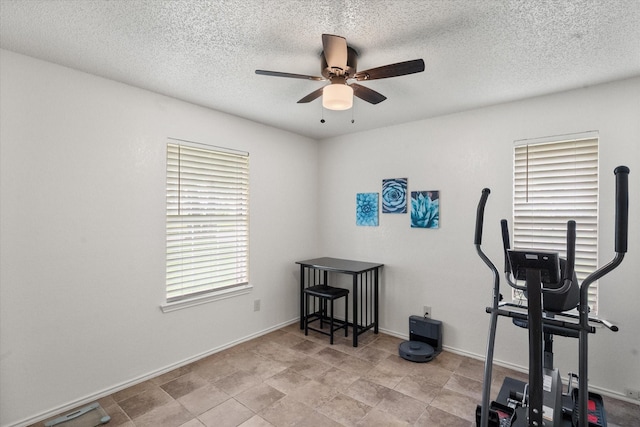 exercise room featuring a textured ceiling, ceiling fan, and baseboards
