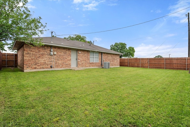 rear view of house with a lawn, central AC unit, and a fenced backyard