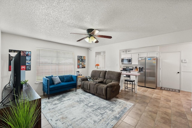 living room featuring a ceiling fan, a textured ceiling, and light tile patterned floors