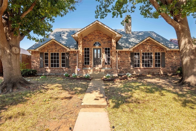 ranch-style house featuring fence, a chimney, a front lawn, and brick siding
