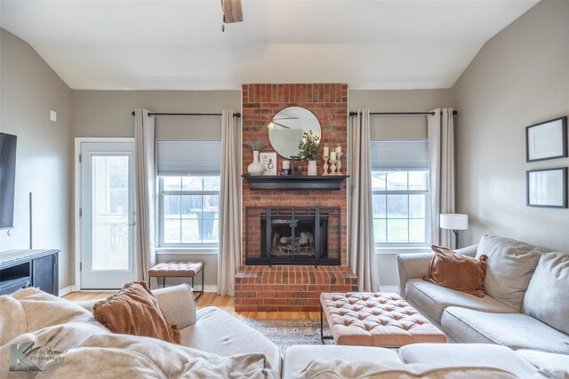 living room featuring baseboards, a ceiling fan, a brick fireplace, and wood finished floors