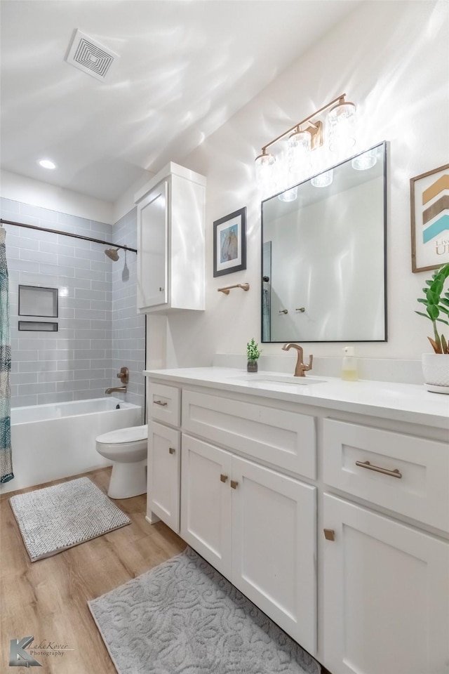 full bath with visible vents, wood finished floors, vanity, toilet, and shower / bathtub combination with curtain