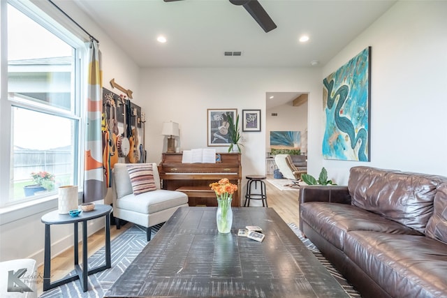 living room with a wealth of natural light, a ceiling fan, wood finished floors, and visible vents