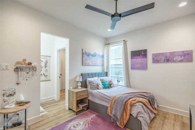 bedroom with baseboards, a ceiling fan, and light wood-style flooring