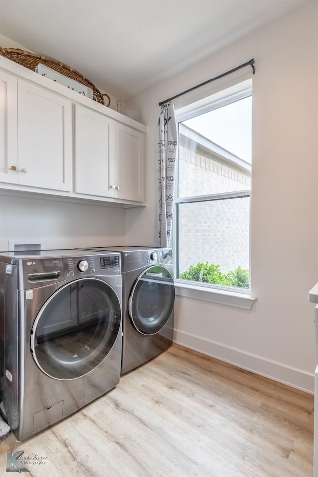 clothes washing area featuring baseboards, washer and clothes dryer, cabinet space, and wood finished floors