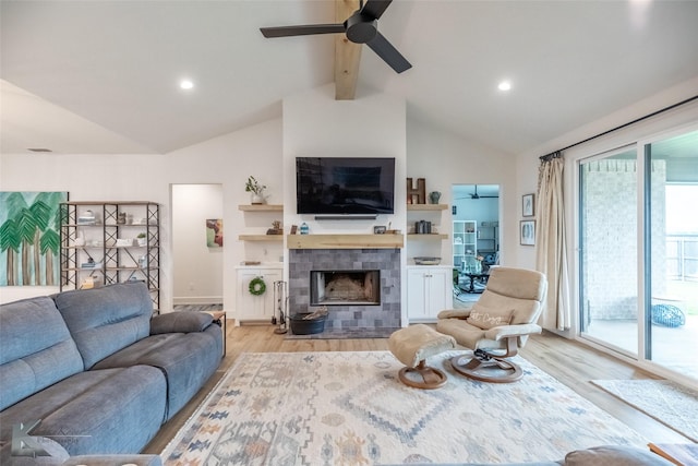 living area with ceiling fan, light wood finished floors, a fireplace, recessed lighting, and beamed ceiling