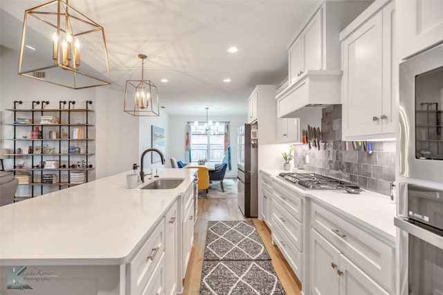 kitchen with light wood-style floors, a sink, an inviting chandelier, stainless steel appliances, and recessed lighting