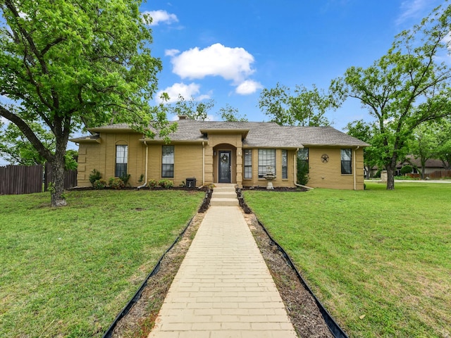 single story home featuring brick siding, fence, and a front yard
