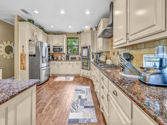 kitchen with decorative backsplash, visible vents, light wood-type flooring, dark stone counters, and stainless steel appliances