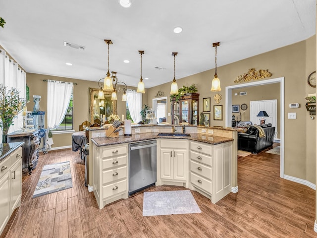kitchen with stainless steel dishwasher, a sink, light wood-style floors, and visible vents