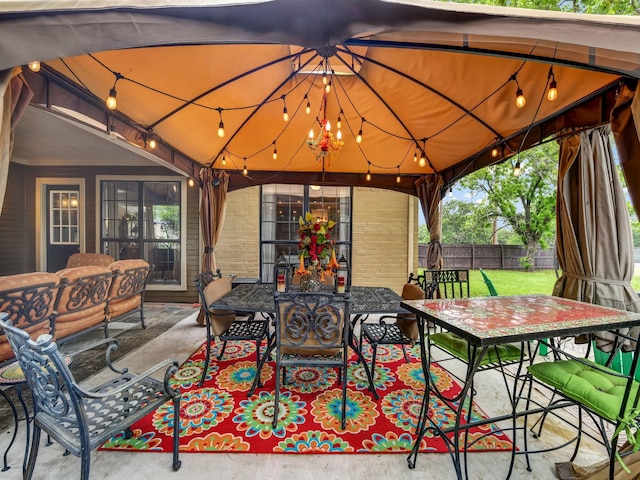 view of patio featuring fence, outdoor dining area, and a gazebo