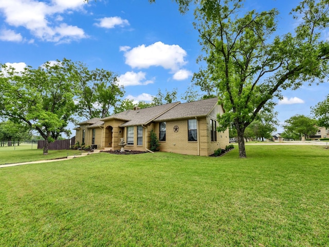 single story home featuring brick siding, fence, and a front lawn