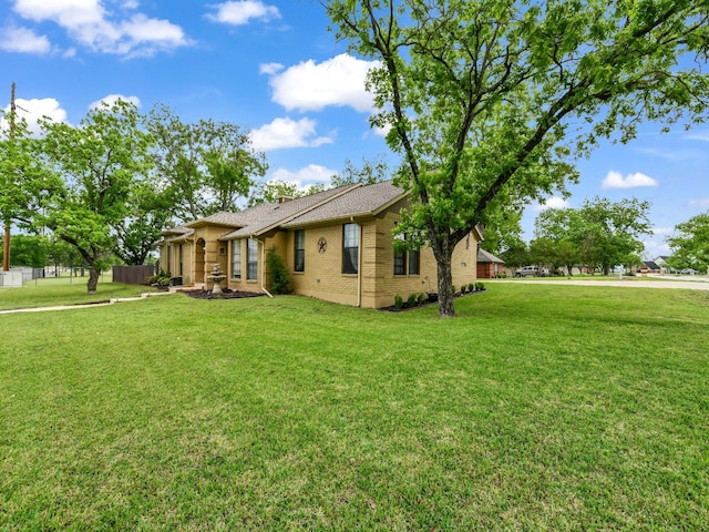view of front facade with brick siding, fence, and a front yard