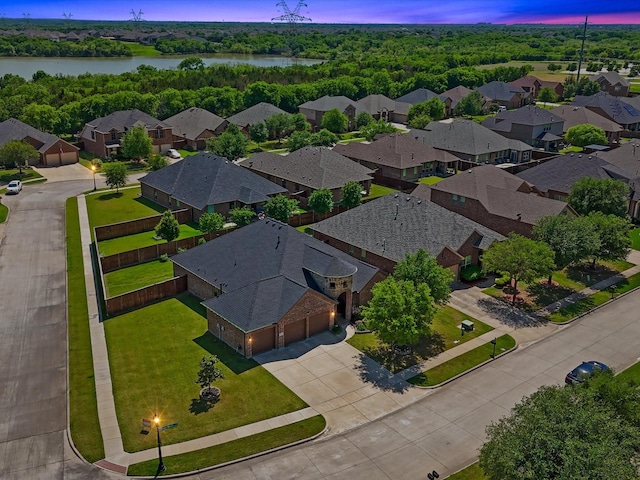 aerial view at dusk with a water view and a residential view