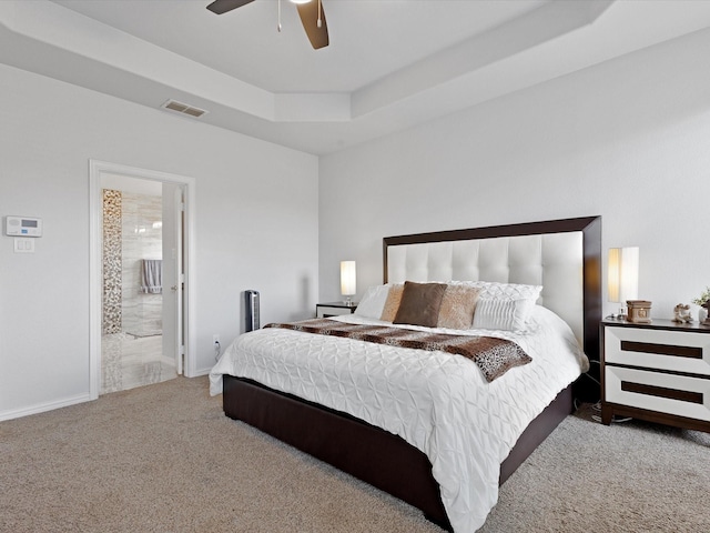 bedroom with connected bathroom, carpet, a ceiling fan, a tray ceiling, and visible vents