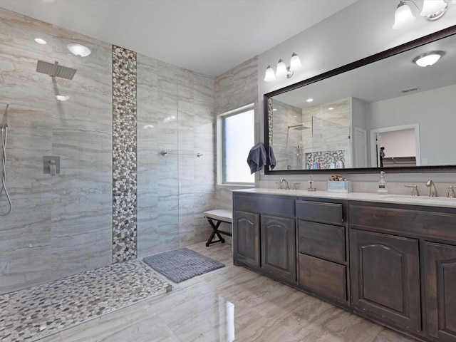 full bathroom featuring double vanity, a sink, walk in shower, and tile walls