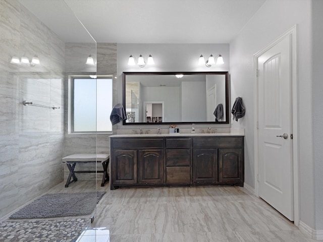 bathroom featuring double vanity, a sink, marble finish floor, and walk in shower
