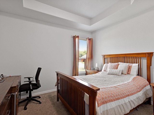 carpeted bedroom featuring a tray ceiling and baseboards