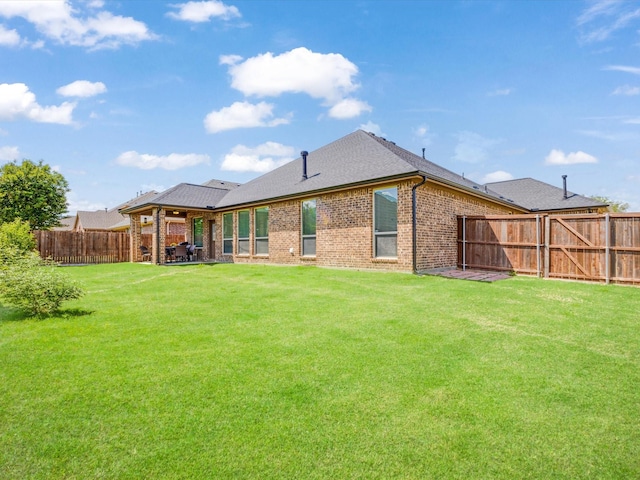 back of property with a lawn, brick siding, and a fenced backyard