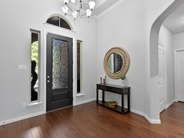 entryway featuring crown molding, wood finished floors, baseboards, a chandelier, and arched walkways