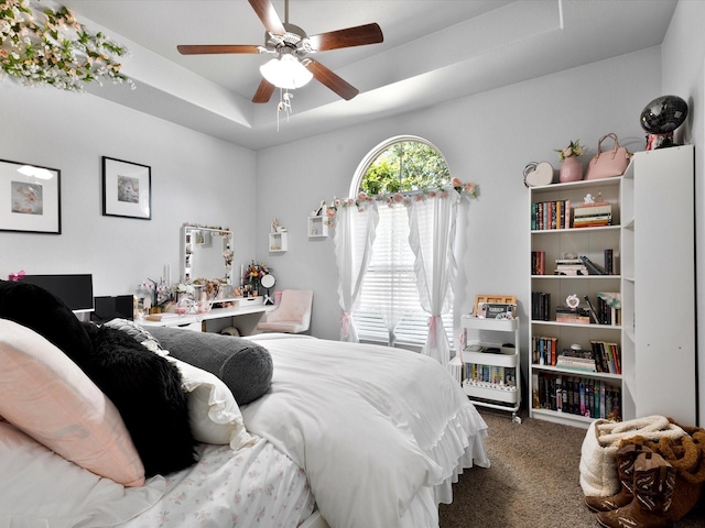 carpeted bedroom featuring a ceiling fan and a tray ceiling
