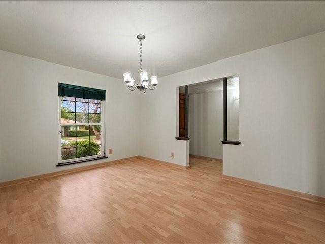 empty room featuring baseboards, light wood-style flooring, and a notable chandelier