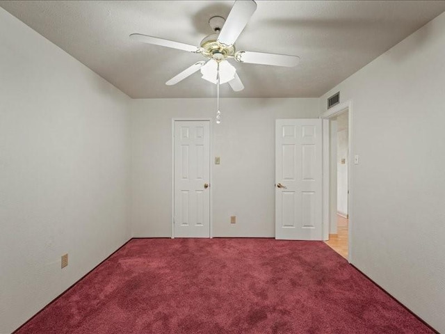 carpeted spare room featuring a ceiling fan and visible vents