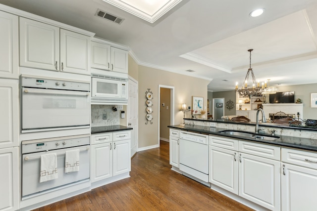 kitchen with visible vents, dark wood-style flooring, white appliances, a chandelier, and a sink