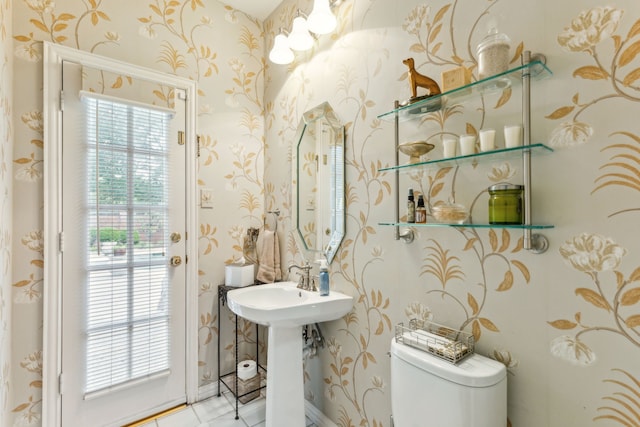 half bath with tile patterned floors, toilet, and wallpapered walls