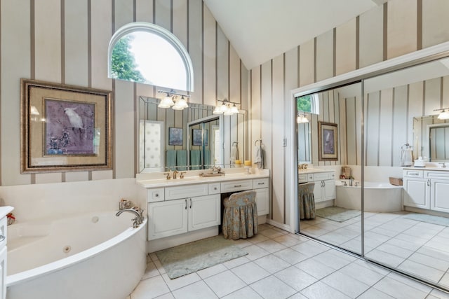 bathroom with two vanities, tile patterned flooring, a whirlpool tub, and a wealth of natural light