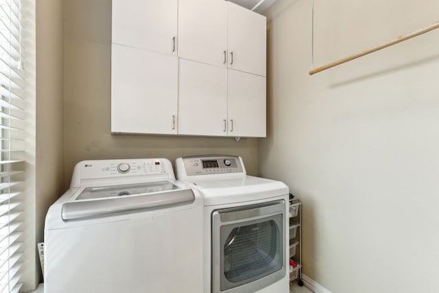 clothes washing area featuring cabinet space and washer and clothes dryer