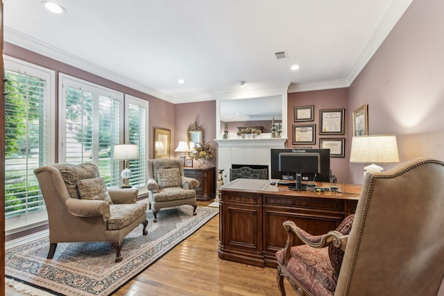 home office with light wood-type flooring, recessed lighting, a tiled fireplace, and ornamental molding